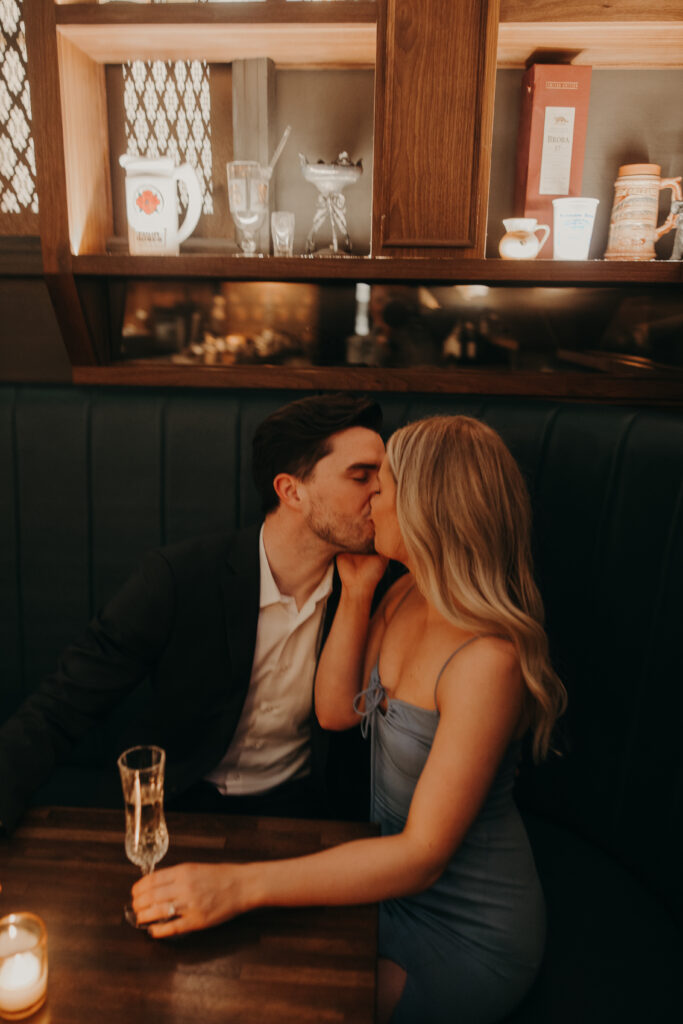 engaged couple having drinks in moody bar