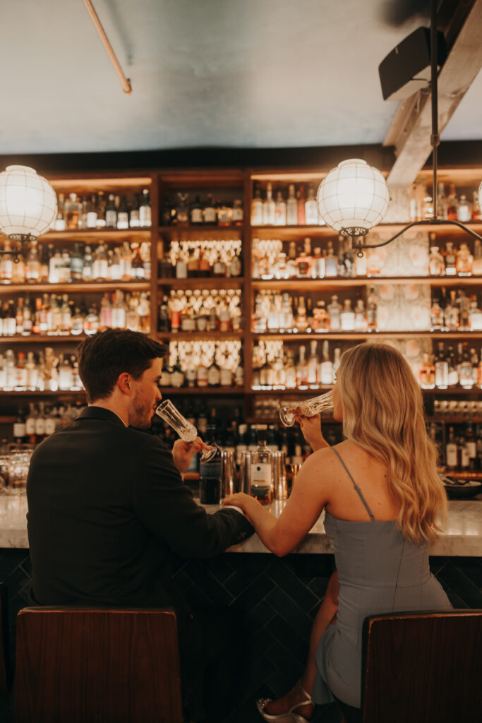 engaged couple having drinks in moody bar