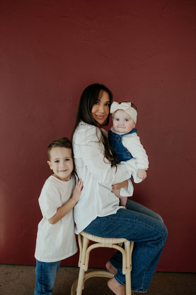 mother and children smiling and snuggling together in portrait with neutral backdrop and soft, even lighting