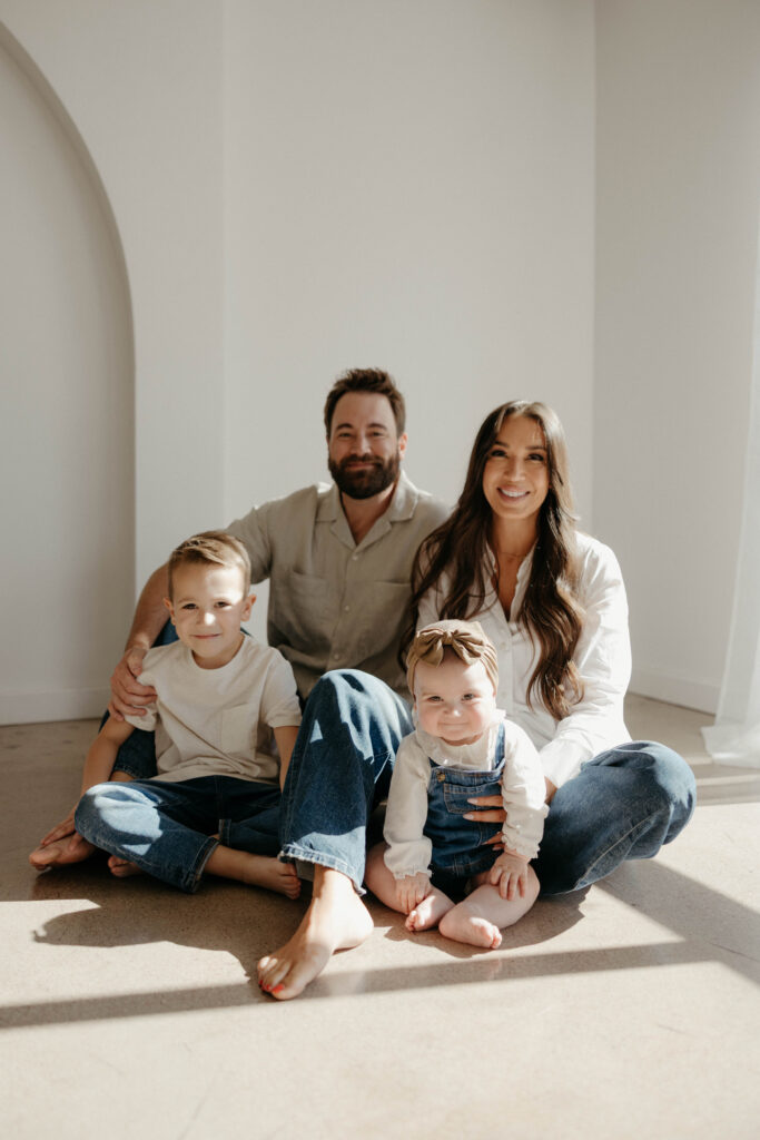 Family smiling together during a studio photoshoot with soft natural lighting