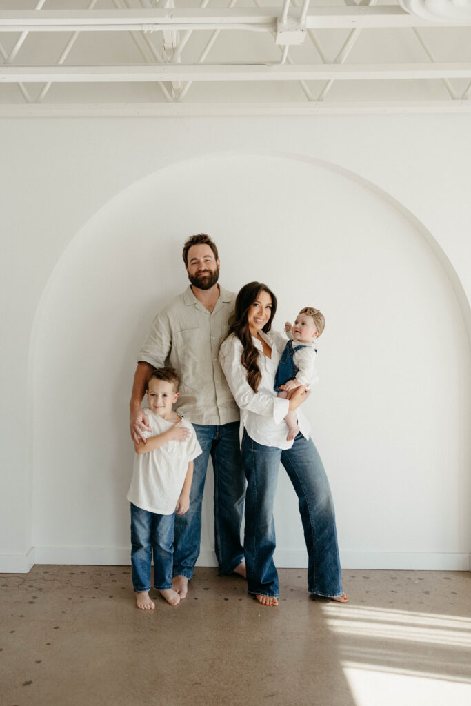 Family smiling together during a studio photoshoot with soft natural lighting