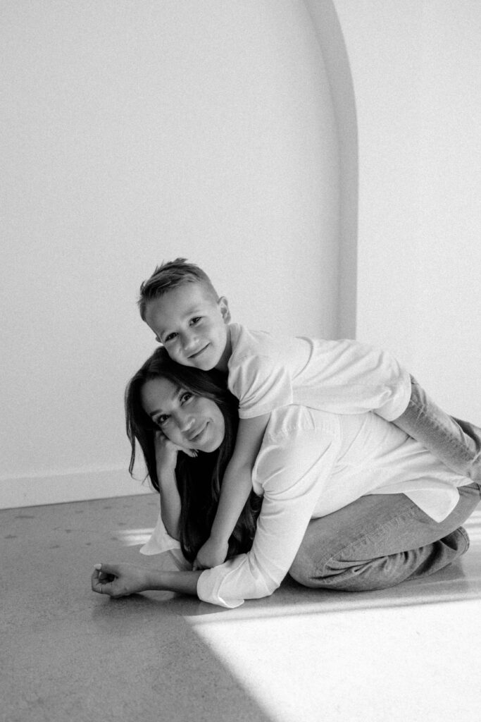 mother and son smiling together during a studio photoshoot with soft natural lighting